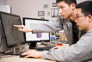 engineers discussing molds in front of computers in office