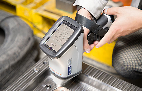 worker holding a spectrograph analyzing stainless steel